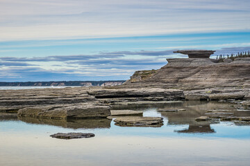 the rugged shoreline of the St Lawrence estuary, with rocky formations sculpted by erosion near Cap...