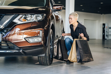 Lower underside happy satisfied woman customer female buyer client in black shirt choose auto want to buy new automobile in car showroom vehicle salon dealership store motor show indoor. Sales concept
