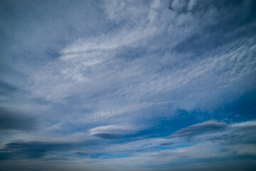 Lenticular and cirrus clouds against blue sky. Sky background