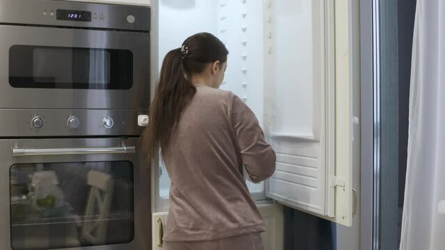 Woman cleaning the empty integrated refrigerator built into the white kitchen housing. High quality 4k footage