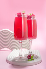 Red mimosas cocktail. Classic mimosa drink with raspberry juice, raspberry and mint decor. Summer bar menu concept, copy space