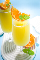 Classic summer mimosas cocktail, with orange juice, on  light blue background. Summer bar menu concept copy space