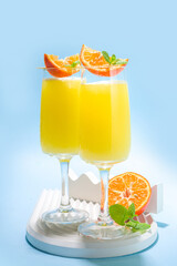 Classic summer mimosas cocktail, with orange juice, on  light blue background. Summer bar menu concept copy space