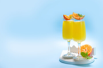 Classic summer mimosas cocktail, with orange juice, on  light blue background. Summer bar menu concept copy space