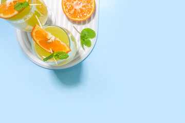 Classic summer mimosas cocktail, with orange juice, on  light blue background. Summer bar menu concept copy space