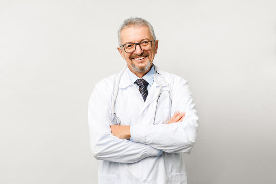 Portrait Of An Elderly Male Doctor On A White Background. Friendly Doctor Smiling While Looking At The Camera.