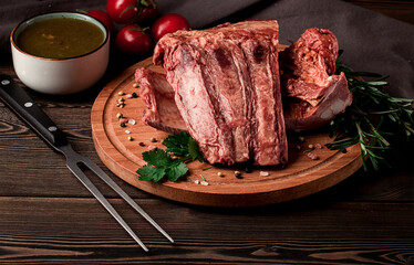 Smoked pork ribs, on a wooden table, top view, sauce, tomatoes and spices, close-up, vertical, no people,