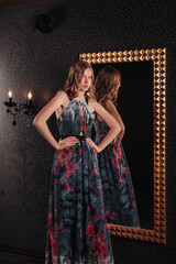 Portrait of pretty cute teenager girl in an elegant dress at mirror