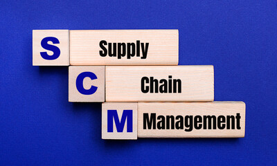 On a bright blue background, light wooden blocks and cubes with the text SCM Supply Chain Management