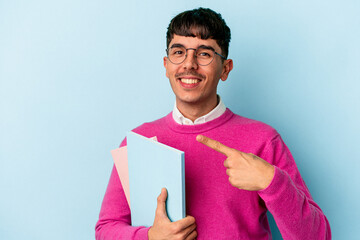 Young mixed race student man isolated on blue background smiling and pointing aside, showing something at blank space.