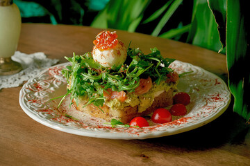 Avocado toast with salmon, rucola and poached egg in white plate on wooden background
