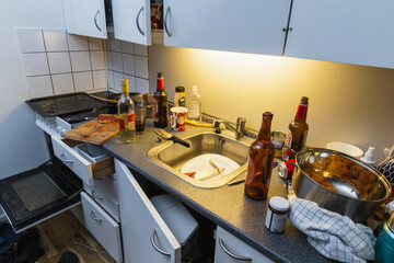Messy kitchen after party. Beer bottles, plates in a sink, wine bottle