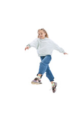 Dynamic portrait of little girl, kid in casual clothes jumping, having fun isolated on gray studio background.