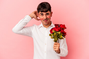 Young mixed race man holding a bouquet of flowers isolated on pink background being shocked, she has remembered important meeting.