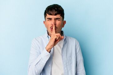 Young mixed race man isolated on blue background keeping a secret or asking for silence.
