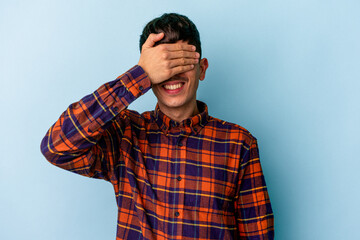 Young mixed race man isolated on blue background covers eyes with hands, smiles broadly waiting for a surprise.