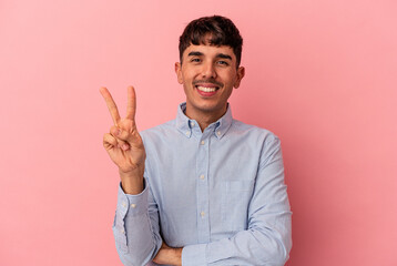 Young mixed race man isolated on pink background joyful and carefree showing a peace symbol with fingers.