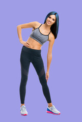 Fototapeta na wymiar Full body portrait image of young happy smiling bright vivid blue haired slim woman doing fitness stretching exercise, isolated over violet purple color background