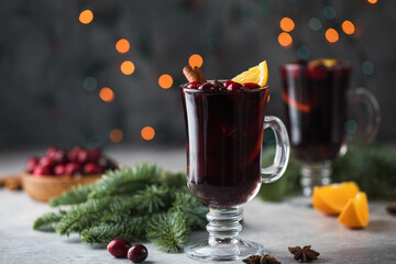  Glasses with homemade mulled wine on a Christmas background with branches of a Christmas tree, cranberries and bokeh.