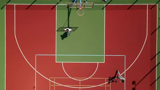 Aerial yop down view of two young male friends playing basketball on court outdoors