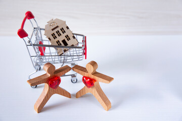 Couple of people byuing a house. Wooden couple of people toy figures  stand near a wooden house.