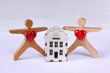 Couple of people byuing a house. Wooden couple of people toy figures  stand near a wooden house.