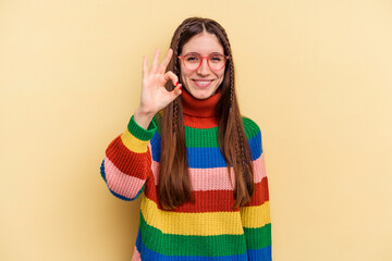 Young caucasian woman isolated on yellow background cheerful and confident showing ok gesture.
