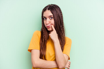 Young caucasian woman isolated on green background unhappy looking in camera with sarcastic expression.