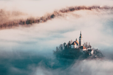 amazing panorama of Lake Bled Blejsko Jezero on a foggy morning with the Pilgrimage Church of the Assumption of Maria on a small island and Bled Castle and Julian Alps in backgroud