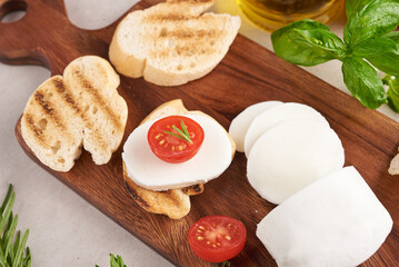 Fresh bruschetta with tomatoes, mozzarella cheese and basil on a cutting board. Traditional italian appetizer or snack, antipasto. Top view. Flat lay. Ciabatta with cherry tomato.