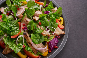 Grilled steak with fresh vegetable, sweet pepper, tomatoes, red onion, pink pepper and spices. Home made tasty food. Concept for tasty and healthy meal. Black stone background. Pork steak with salad