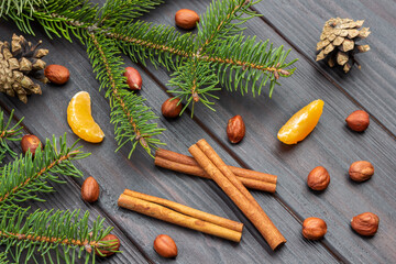 Cinnamon sticks and nuts on dark wooden background.