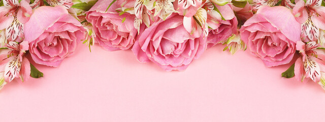 Beautiful pink rose and alstroemeria flowers in a top border on coral paper