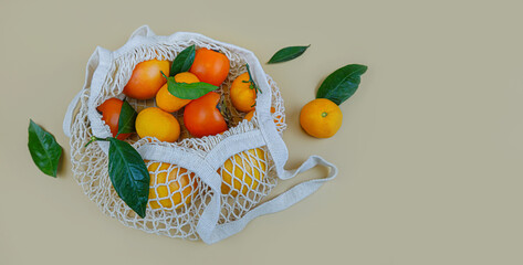 White string bag with orange fruits. Ripe persimmons, tangerines and grapefruit close up. Flat lay, copy space.