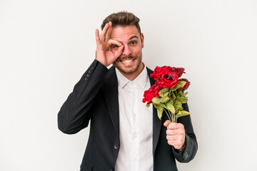 Young caucasian man holding bouquet of flowers isolated on white background excited keeping ok gesture on eye.