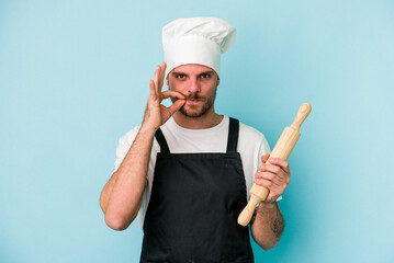 Young baker man isolated on blue background with fingers on lips keeping a secret.