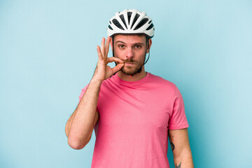 Young caucasian man with bike helmet isolated on blue background with fingers on lips keeping a secret.