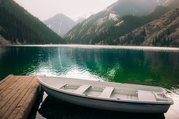 Boat in the pearl mountain lake Kolsay