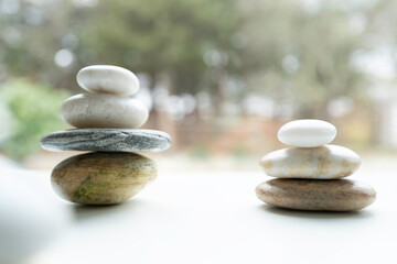 Two sets of Zen rocks stacked on the white promenade near tranquil pond in the woods