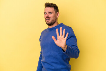 Young caucasian man isolated on yellow background being shocked due to an imminent danger