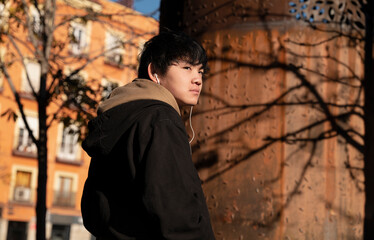 Asian teenage boy with earphones on street. Madrid. Spain