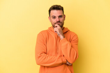 Young caucasian man isolated on yellow background thinking and looking up, being reflective, contemplating, having a fantasy.