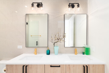 A luxury bathroom with a wooden vanity cabinet, square mirrors, and a white marble countertop.