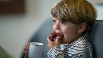 Toddler drinks from mug. Child drinking from cup in morning breakfast.