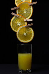 Orange and orange juice on a black background. Orange slices on a rope on a dark background. Freshly squeezed orange juice