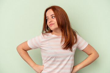 Young caucasian woman isolated on green background dreaming of achieving goals and purposes