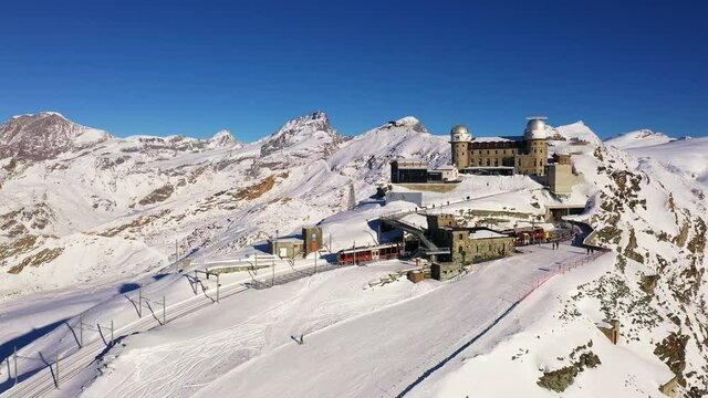  Aerial drone footage of an iconic cogwheel Gornergrat train reaching the summit station at 300m in Zermatt  in the Alps in Valais, on a sunny winter day