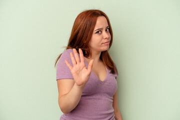 Young caucasian woman isolated on green background rejecting someone showing a gesture of disgust.