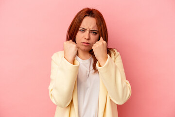Young caucasian woman isolated on pink background showing fist to camera, aggressive facial...