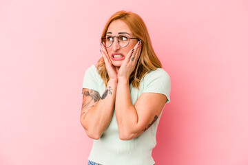 Young caucasian woman isolated on pink background scared and afraid.